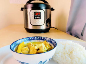 yellow curry chicken in bowl with rice and instant pot in the background