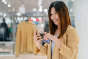 asian woman looking at phone in retail store