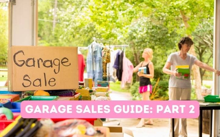 Garage sale on cardboard sign, rack of clothes, women shopping with trees in the background