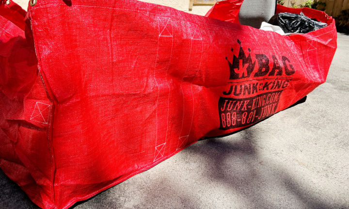 side view of Red Dumpster Bag with text BAG, Junk King, Junk-king.com, 888-888-JUNK