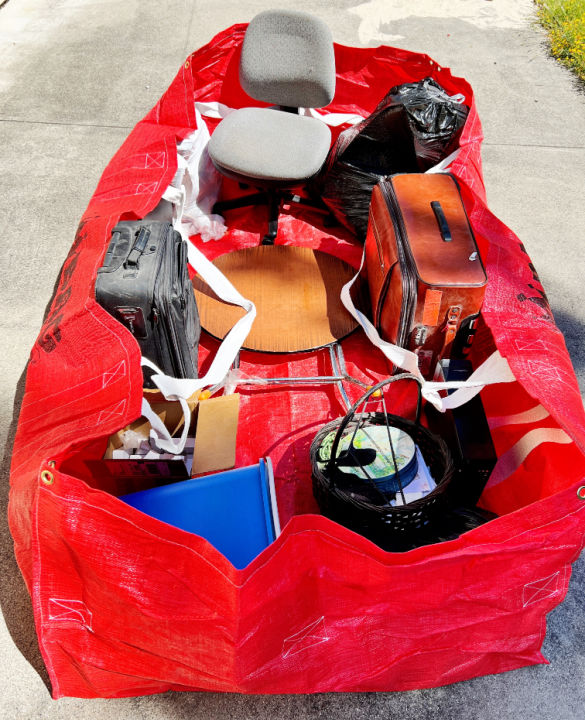 Top View of Red Dumpster Bag with luggage, trash cans, office chair, round table, and garbage bag