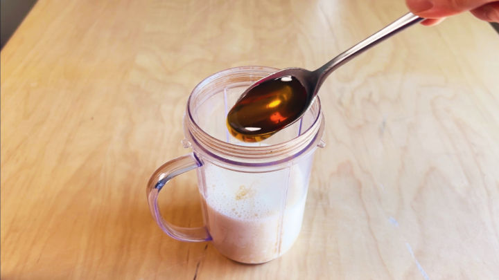 adding honey in teaspoon into blender cup of soy milk