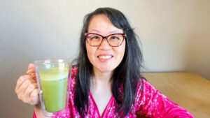 asian woman holding glass mug with iced matcha latte