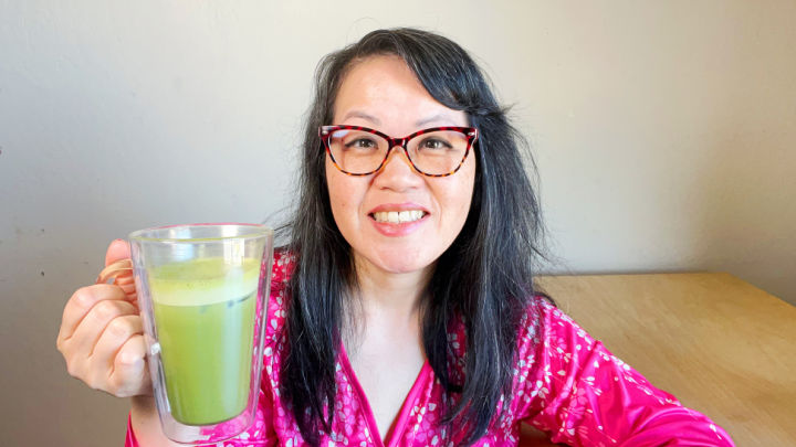 asian woman holding glass mug with iced matcha latte