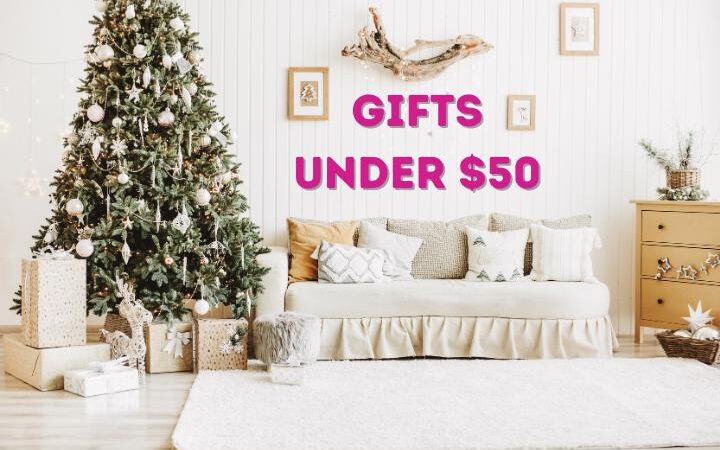 Text: Gifts Under $50, Image: White living room with Christmas tree on left and gifts and cozy couch in the middle