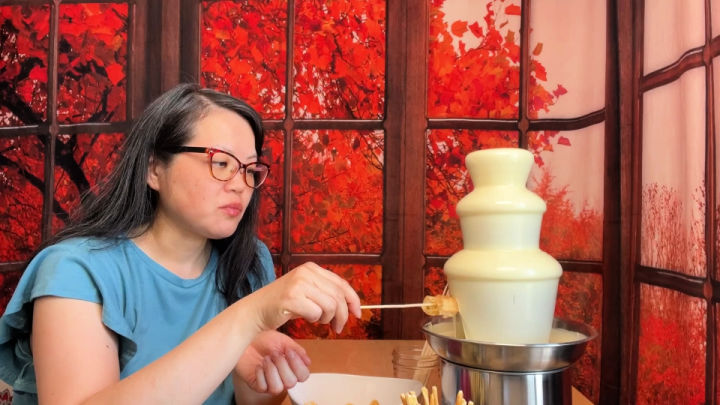 woman dipping waffle into a white chocolate fountain