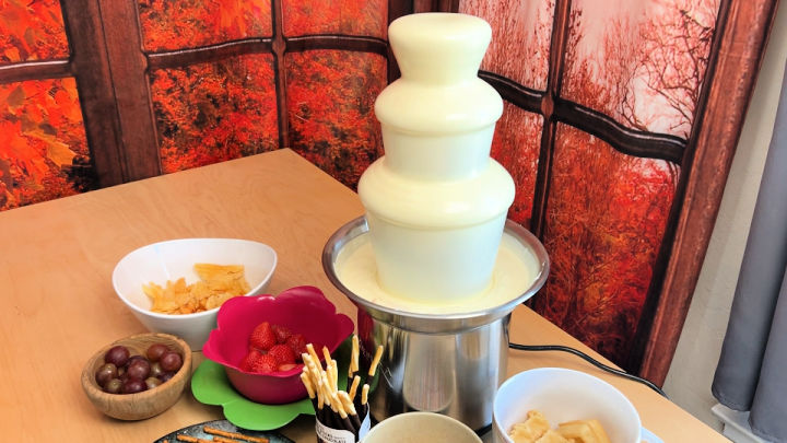 white chocolate fountain with dipping items around on a table